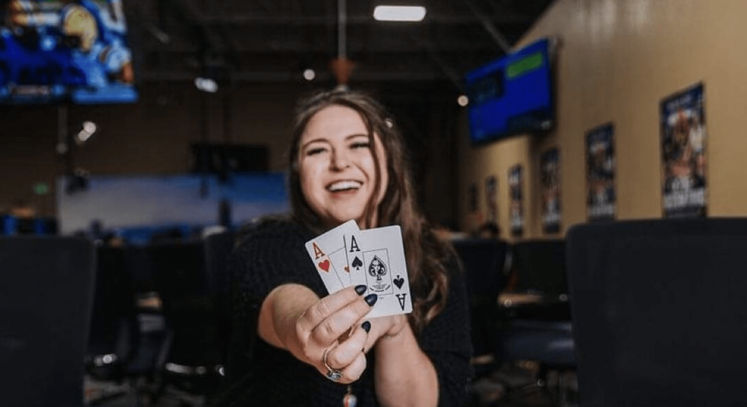 Caitlin Comeskey holding 2 ace cards at the camera